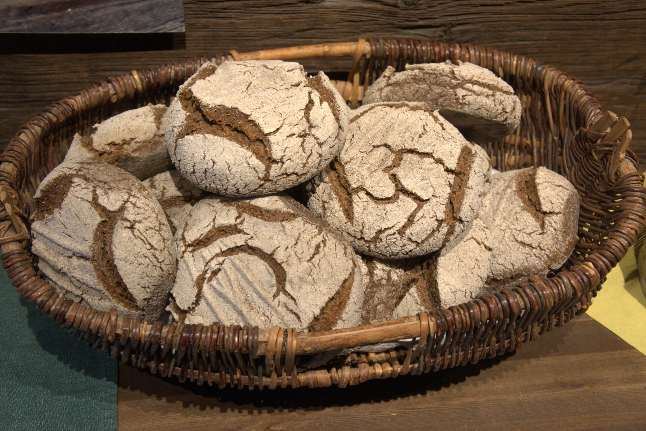 Basket of round, cracked-crust bread rolls dusted with flour in a woven basket