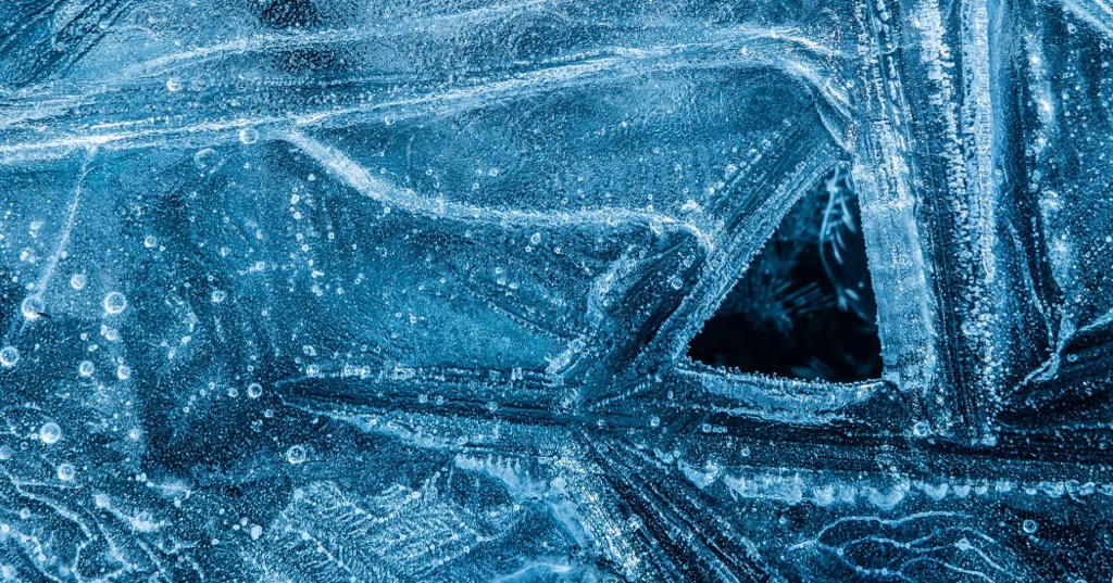 Close-up of blue frost crystals on a window with a triangular opening revealing darkness inside.